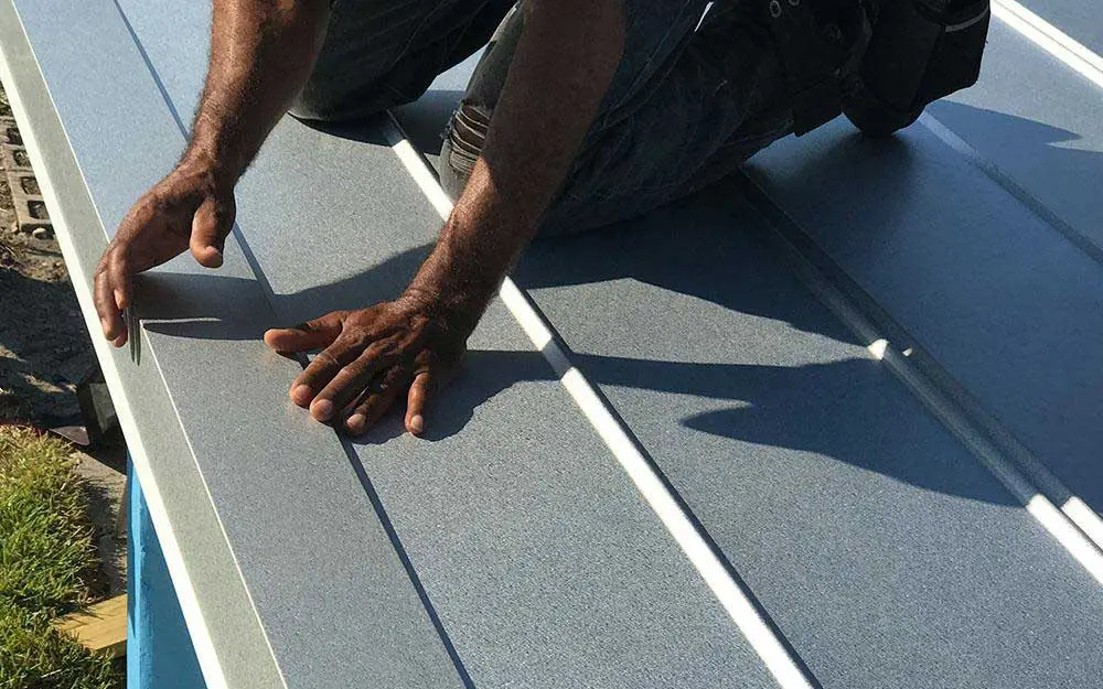 A person installing edging on a metal roof.